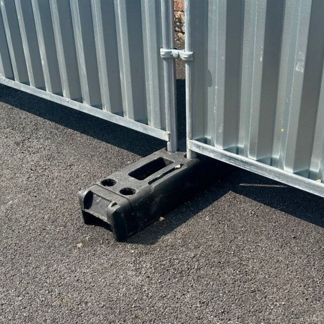14 kg plastic block holding a construction fence, used for stabilizing temporary barriers