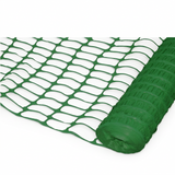 Green plastic mesh safety netting shown partially unrolled from a roll on a white background.